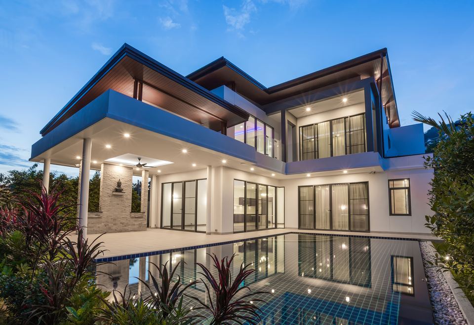 Modern Naples home with a pool, lit at dusk